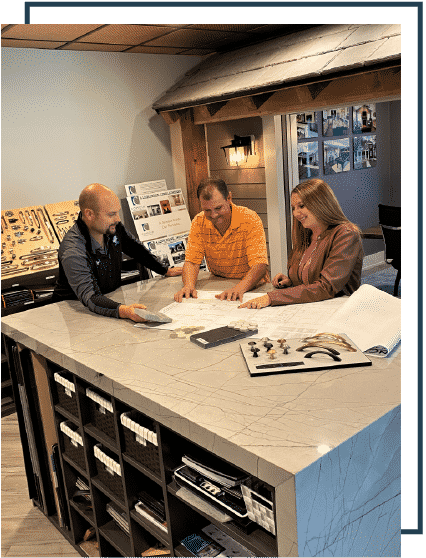 close up of kitchen with various design materials arranged on it, three people discussing housing and design projects.