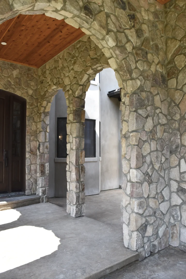 Arched stone porch with a wood ceiling and dark entry door.