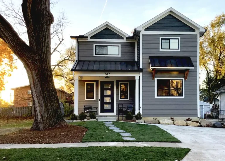 Dark-sided custom home with white trim, front entry and a path across the lawn.