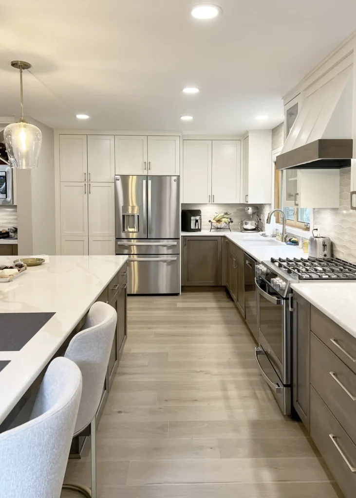 Kitchen range and white cabinetry beside an island with seating.