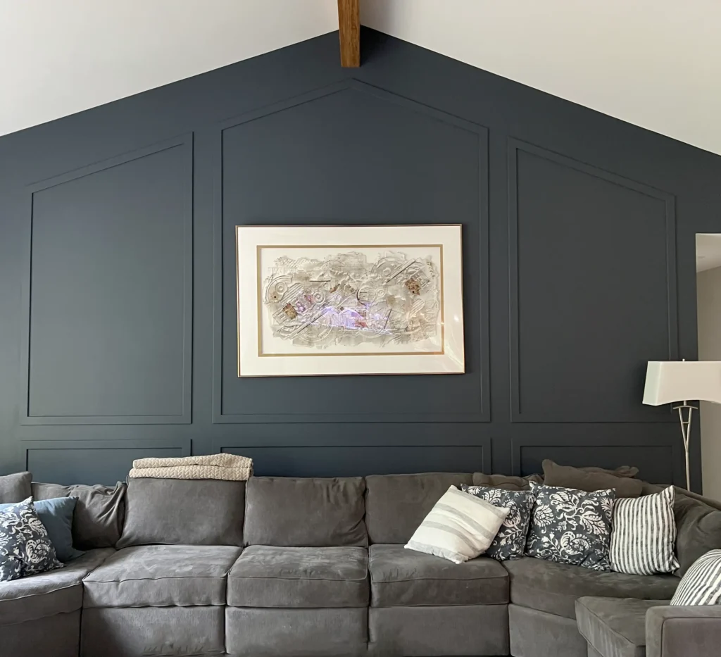 Sectional seating in front of a dark paneled living-room accent wall.