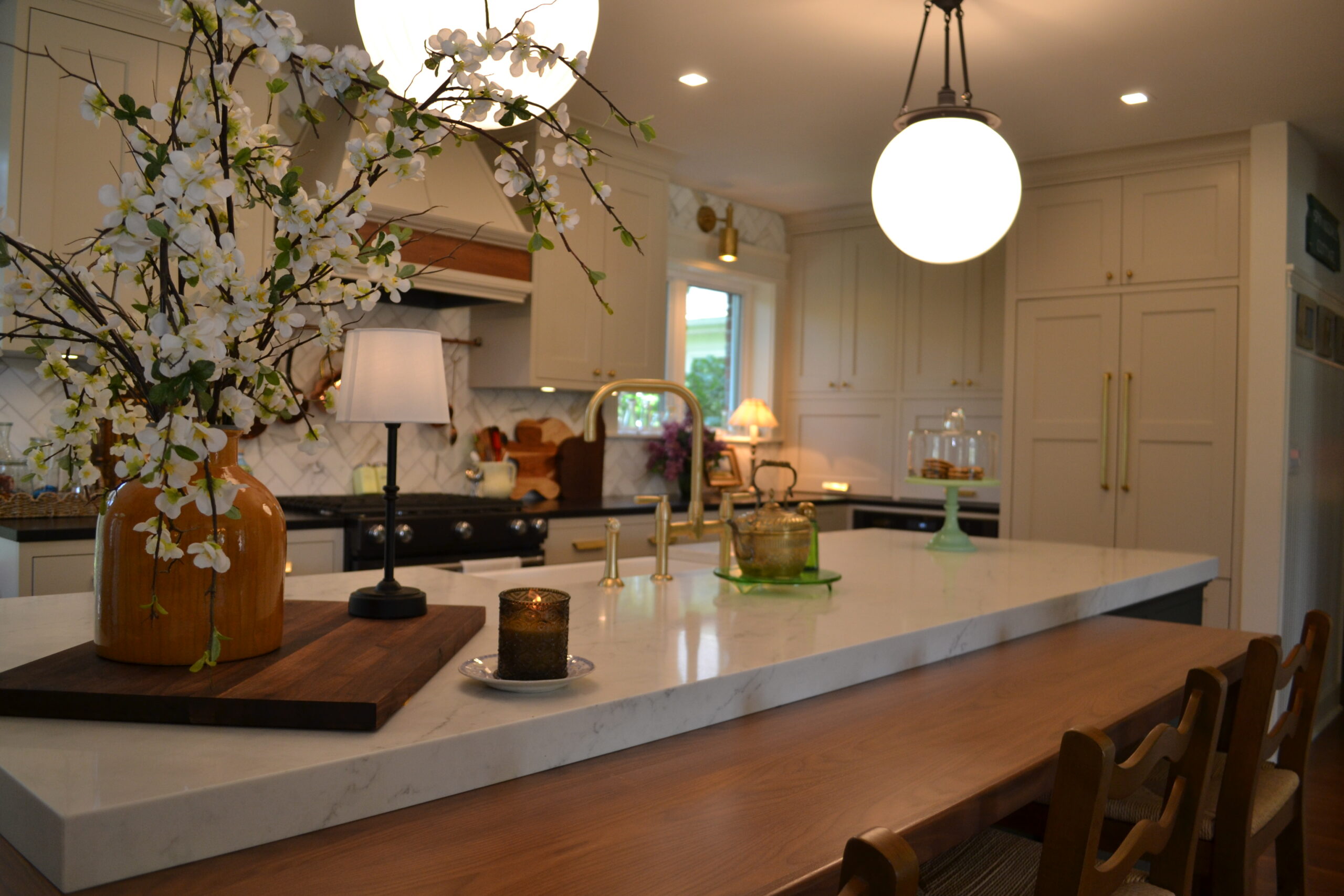 Kitchen island with globe pendant lights, warm wood cabinetry and open display shelving.